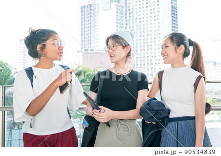 Three young multi-racial women smiling and talking to each other. 90534839