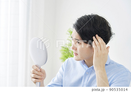 自宅で鏡を見てヘアチェックする男性 90535014