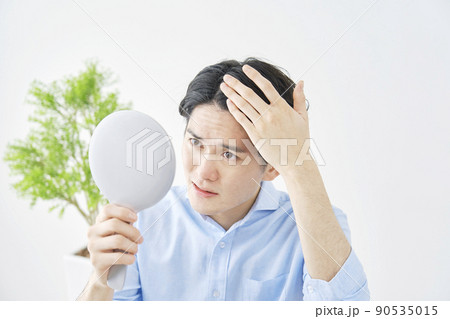 リビングで鏡を見てヘアチェックする男性 90535015