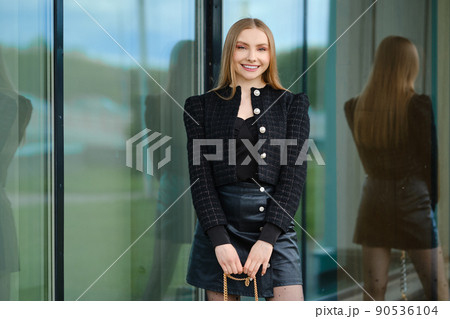 Smiling woman standing by the building with large glass windows Smiling woman standing by the building with large glass windows 90536104
