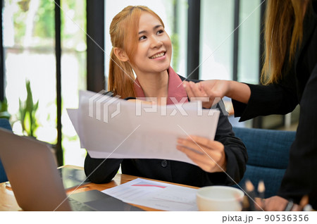 Female office worker employee smiling while talking with her friendly female boss. 90536356