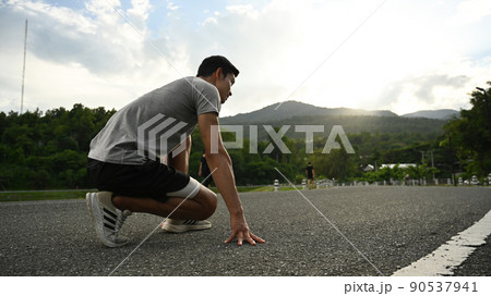 Young sportsman in starting position, ready to run outdoors in the morning. Health and sport concept Young sportsman in starting position, ready to run outdoors in the morning. Health and sport concept 90537941