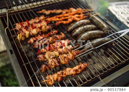 Close up view of men hands roasting barbecue on fire grill. Close up view of men hands roasting barbecue on fire grill. 90537984