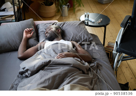 African American man lying on bed under blanket and resting because feeling himself bad 90538536