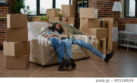 African american partners unpacking living room couch and furniture after moving in new household property. Taking break from interior decoration, on moving day for new beginnings. African american partners unpacking living room couch and furniture after moving in new household property. Taking break from interior decoration, on moving day for new beginnings. 90538604