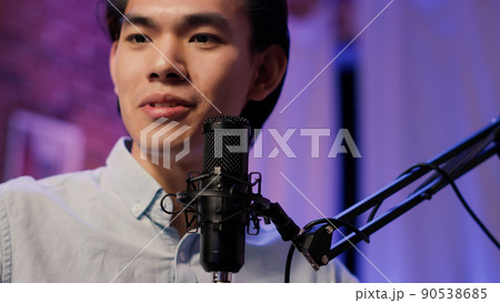 Asian man talking to channel audience on podcast show, using recording equipment with microphone to broadcast live discussion. Audio social media episode on channel. Close up. . Asian man talking to channel audience on podcast show, using recording equipment with microphone to broadcast live discussion. Audio social media episode on channel. Close up. . 90538685