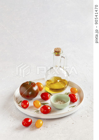 Round tray with different tomato varieties, salt and olive oil Round tray with different tomato varieties, salt and olive oil 90541470