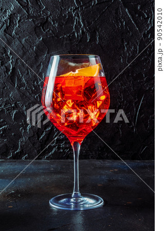 Aperol cocktail with a fresh orange, a side view on a black background 90542010