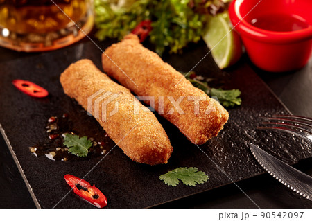 Fried crispy spring rolls with sweet chili sauce, salad and beer on wooden table. Fried crispy spring rolls with sweet chili sauce, salad and beer on wooden table. 90542097