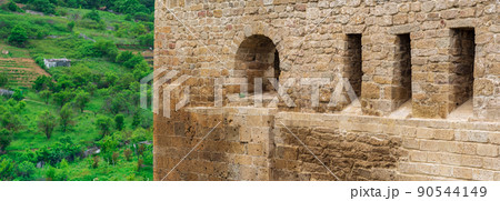 fragment of the wall of a medieval castle, behind which the faubourgs are visible; Naryn-Kala citadel in Derbent 90544149
