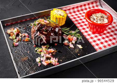 A piece of steak with salad, corn, mushrooms sauce on a blackboard A piece of steak with salad, corn, mushrooms sauce on a blackboard 90544529
