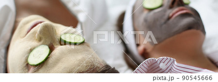 Woman and man friends resting on bed with facial mask and cucumbers Woman and man friends resting on bed with facial mask and cucumbers 90545666