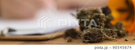 Dried pieces of marijuana on doctors desk fell out of plastic bottle Dried pieces of marijuana on doctors desk fell out of plastic bottle 90545674