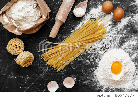 Raw egg pasta with flour on black background 90547677