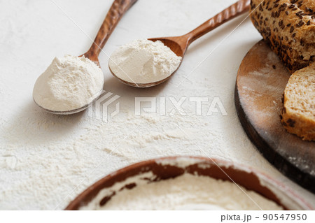 Pile of flour in wooden spoon on white background Pile of flour in wooden spoon on white background 90547950