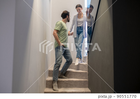 Man supporting woman walking down stairs at home Man supporting woman walking down stairs at home 90551770
