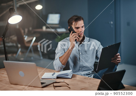 young businessman with a clipboard talking on a smartphone. 90552300