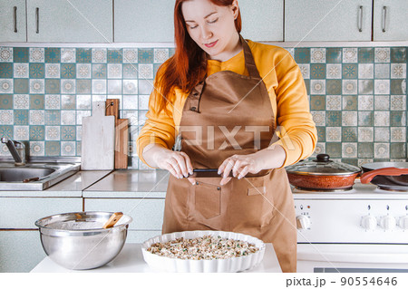 Young woman cooks in home kitchen and photographs food for social media. Blogger writes a culinary blog. Lifestyle, home leisure concept. 90554646