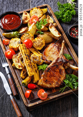 bbq tomahawk pork chop with corn and potatoes bbq tomahawk pork chop with corn and potatoes 90554829
