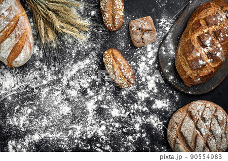 Different bread with flour and spikelets of wheaton black background Different bread with flour and spikelets of wheaton black background 90554983