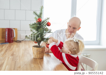 Child with cochlear implant hearing aid having fun with father and small christmas tree - diversity and deafness treatment and medical innovative technologies Child with cochlear implant hearing aid having fun with father and small christmas tree - diversity and deafness treatment and medical innovative technologies 90555142
