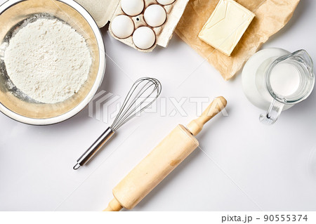 Preparation of the dough. A measurement of the amount of ingredients in the recipe. Ingredients for the dough: flour, eggs, rolling pin, whisk, milk, butter, cream. Top view, space for text 90555374
