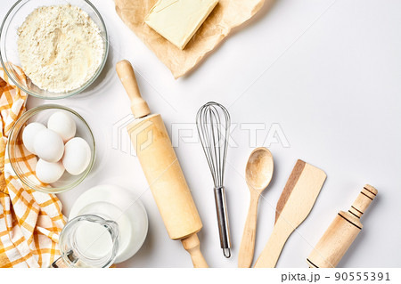 Preparation of the dough. A measurement of the amount of ingredients in the recipe. Ingredients for the dough: flour, eggs, rolling pin, whisk, milk, butter, cream. Top view, space for text 90555391