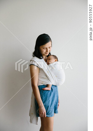 A mum holding her baby. Baby sleeping in sling.  A mum holding her baby. Baby sleeping in sling.  90555927