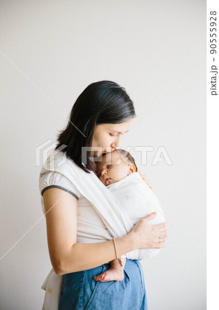 A mum holding her baby. Baby sleeping in sling.  90555928