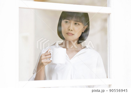 ガラス格子のドアから外を見る若い女性 90556945