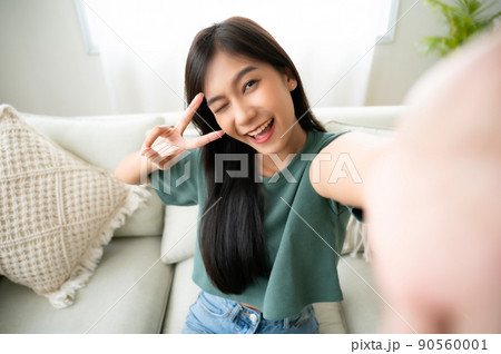 Pretty young asian female with big smile sitting at living room Pretty young asian female with big smile sitting at living room 90560001
