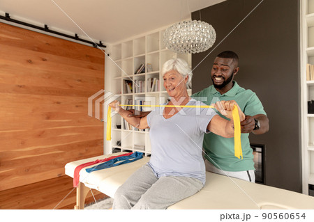 African american male physiotherapist helping senior woman to exercise with resistance bands African american male physiotherapist helping senior woman to exercise with resistance bands 90560654