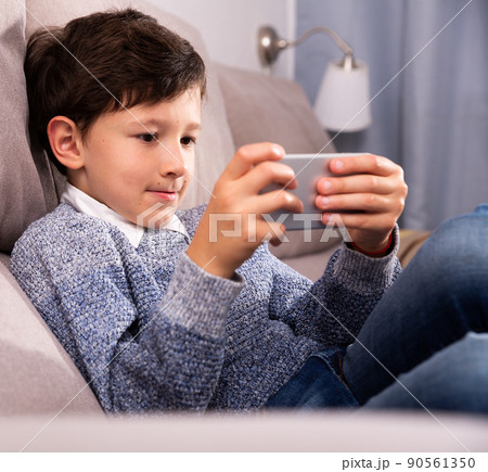Teenager plays on smartphone in home interior 90561350