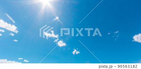 Natural abstract background of bright blue sky and fluffy white clouds on a sunny, light a flare and sun. Natural abstract background of bright blue sky and fluffy white clouds on a sunny, light a flare and sun. 90563182
