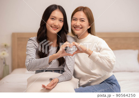 Close up.Asian lesbian couple making heart shape sign hug and smiling with love together. 90564250
