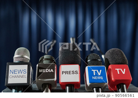 Close-up of microphones of different tv media in front of tribune for speaker at press conference Close-up of microphones of different tv media in front of tribune for speaker at press conference 90566561