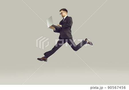 Successful young businessman who is in hurry to do lot of work working on laptop on run. 90567456