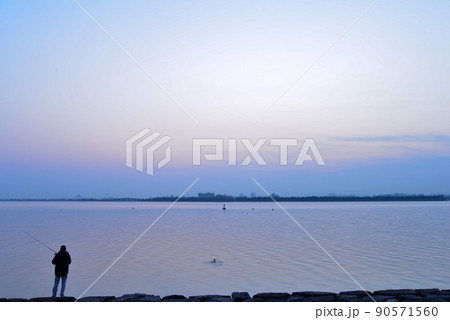 優しい朝の色に包まれた琵琶湖と釣り人、そして水鳥 90571560
