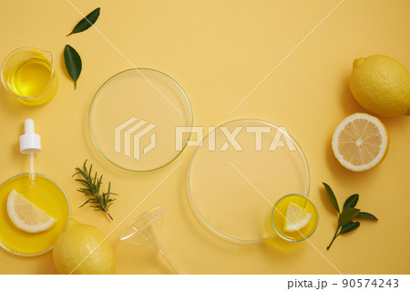 Lemon extract in beaker , flask and dropper lemon and sliced lemon , green leaf in a yellow background with yellow water in petri dish , top view , photography experiment content for advertising 90574243