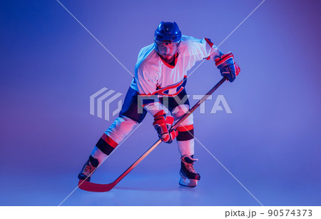 In action. Professional hockey player in sports uniform and protective equipment skating isolated on purple background. Concept of sport, active lifestyle, motion, movement, ad. 90574373
