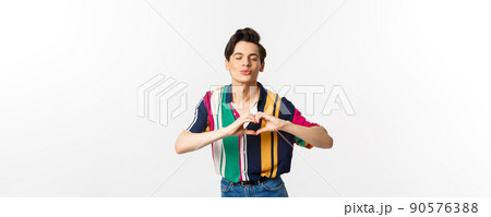 Lovely young man pucker lips and showing heart sign, waiting for kiss, I love you gesture, standing over white background Lovely young man pucker lips and showing heart sign, waiting for kiss, I love you gesture, standing over white background 90576388