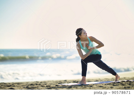 砂浜でヨガをする若い女性 90578671