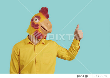 Funny man with chicken head raises his thumb up demonstrates you OK gesture, consent or his support. Funny man with chicken head raises his thumb up demonstrates you OK gesture, consent or his support. 90579020