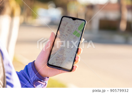 Female hand holds a smartphone with an online navigation app. Close-up. GPS concept 90579932
