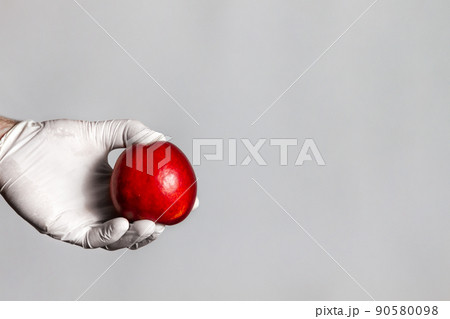 Male hands in medical gloves holding a peach fruit. White background. The concept of GMO foods, vegetables and fruits. Copy space 90580098