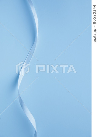 Blue ribbon on a paper background. Background for a greeting card. 90580344