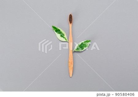 Zero waste. Bamboo toothbrush with leaves. Gray background. Flat lay. The concept of eco-friendly toothbrushes 90580406