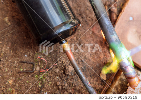 HVAC technician soldering a copper pipe joint for air conditioning HVAC technician soldering a copper pipe joint for air conditioning 90580519
