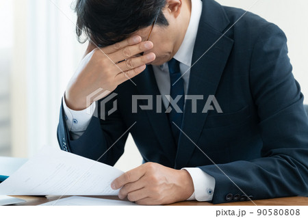 書類を確認して悩むビジネスマン 書類を確認して悩むビジネスマン 90580808