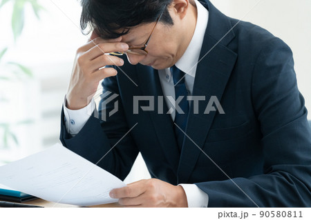 書類を確認して悩むビジネスマン 書類を確認して悩むビジネスマン 90580811